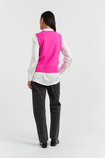 Person wearing a white shirt, black pants, and a bright pink vest on a white background