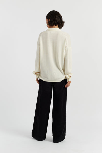 Person wearing a cream blouse and black pants on a white background
