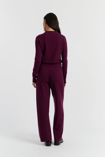 Person wearing a burgundy jumpsuit on a white background