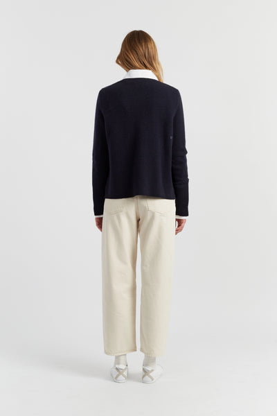 Person wearing a navy sweater and beige pants on a white background