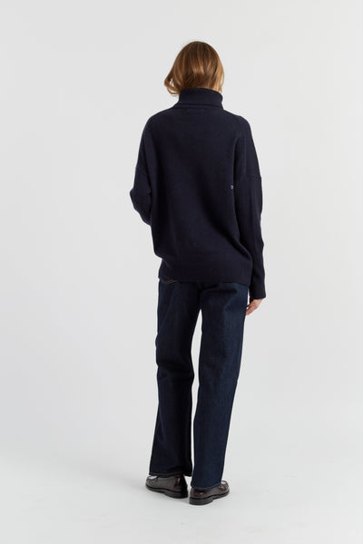 Person wearing a navy sweater and pants on a white background