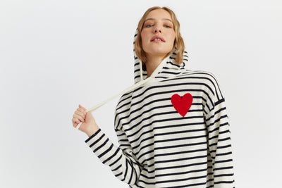 Woman wearing a black and white striped hoodie with a red heart design on a light gray background