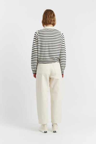 Person wearing a black and white striped shirt and white pants on a white background