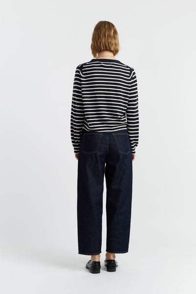 Person wearing a black and white striped shirt and dark jeans on a white background