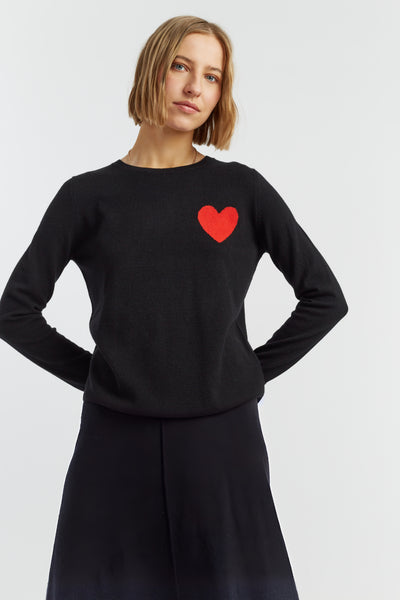 Woman wearing a black sweater with a red heart on a white background