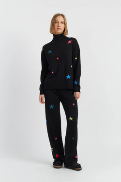 Person wearing a black outfit with colorful star patterns on a white background