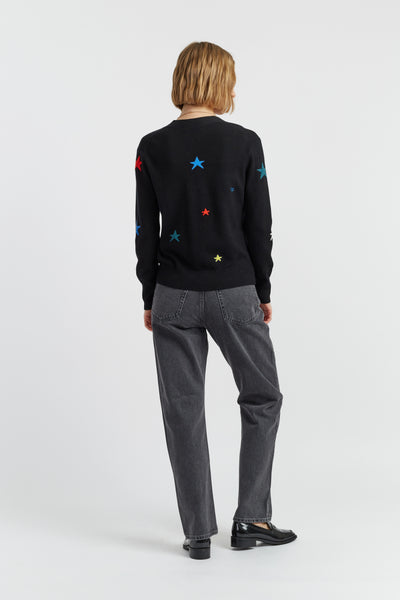 Person wearing a black sweater with colorful star patterns on a white background