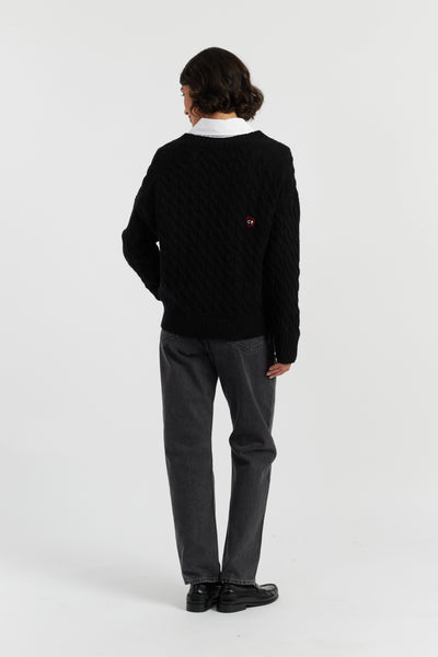 Person wearing a black sweater and gray pants on a white background