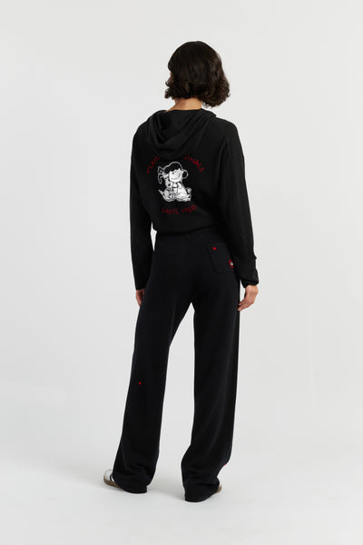 Person wearing a black hoodie and pants with a design on the back, standing against a white background