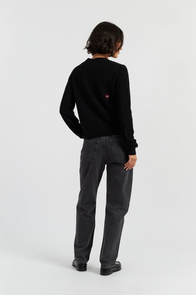 Person wearing a black sweater and gray pants on a white background