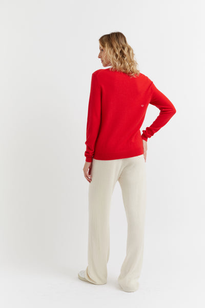 Woman wearing a red sweater and white pants on a white background