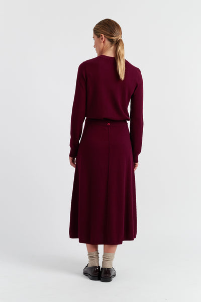 Woman wearing a burgundy dress and sweater set on a white background