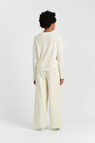 Person wearing a cream-colored outfit on a white background