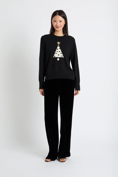 Woman wearing a black sweater with a Christmas tree design on a white background