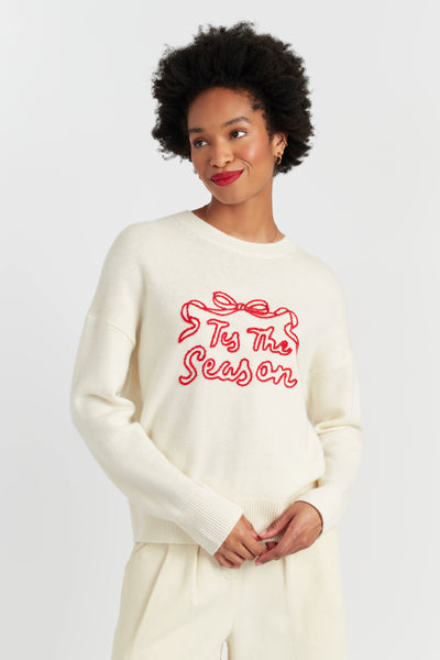 Woman wearing a white sweater with red text on a plain background