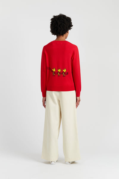 Person wearing a red sweater with a design on the back, standing against a white background