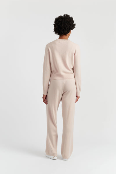 Person wearing a beige sweater and pants set on a white background