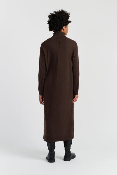 Person wearing a long brown coat on a white background