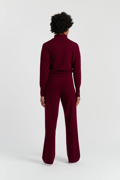 Person wearing a burgundy jumpsuit on a white background