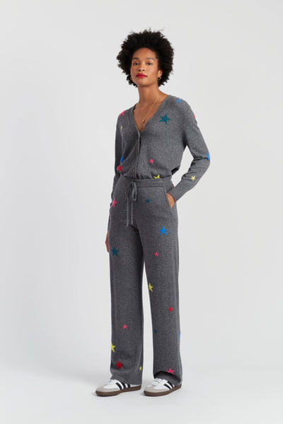 Woman wearing a gray jumpsuit with colorful star patterns on a white background