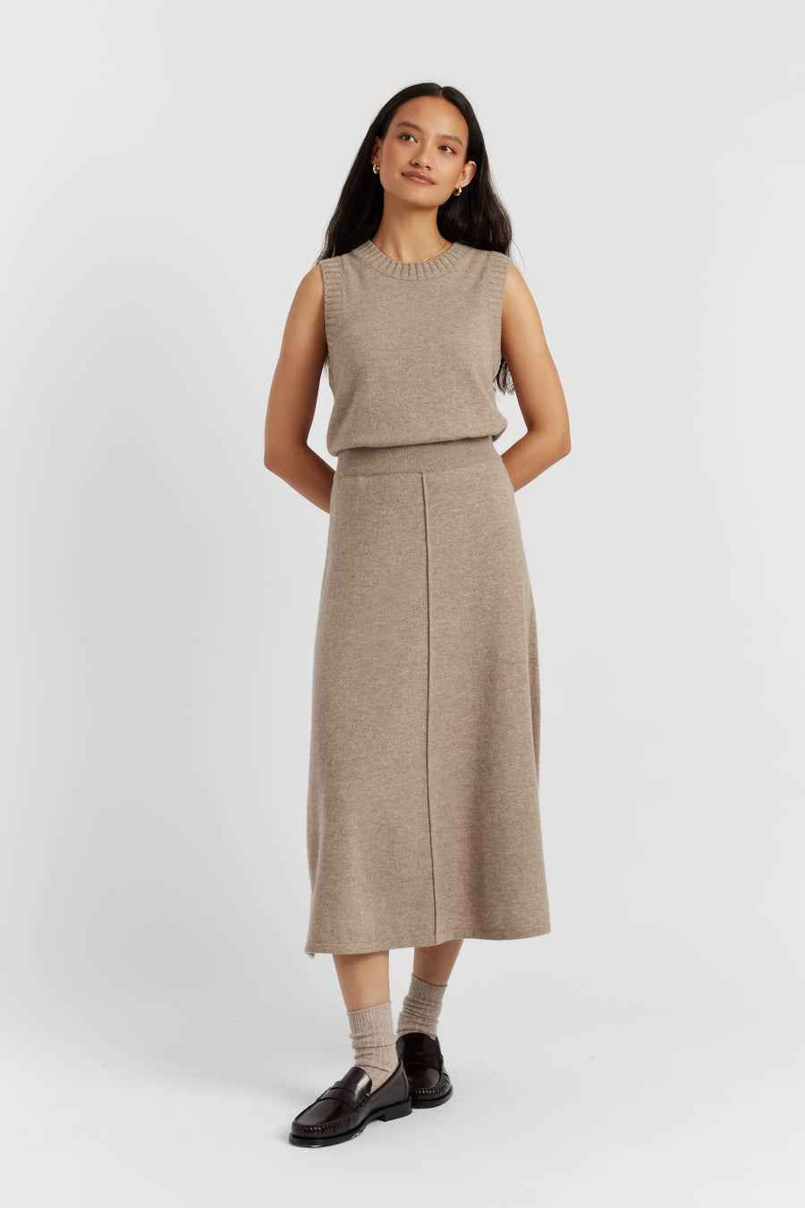 Woman wearing a beige sleeveless top and skirt set on a white background