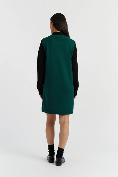 Person wearing a green dress with black sleeves on a white background