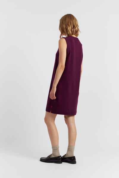 Person wearing a sleeveless purple dress on a white background