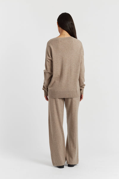 Person wearing a beige sweater and pants set on a white background