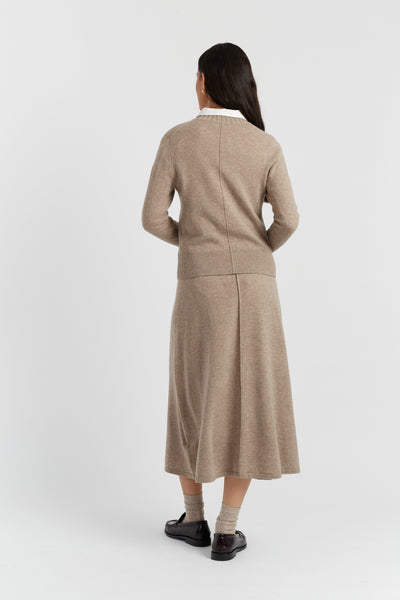 Woman wearing a beige cardigan and skirt set on a white background