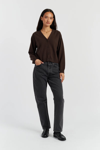 Woman wearing a brown shirt and dark jeans on a white background