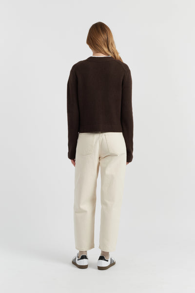 Person wearing a dark sweater and light-colored pants on a white background