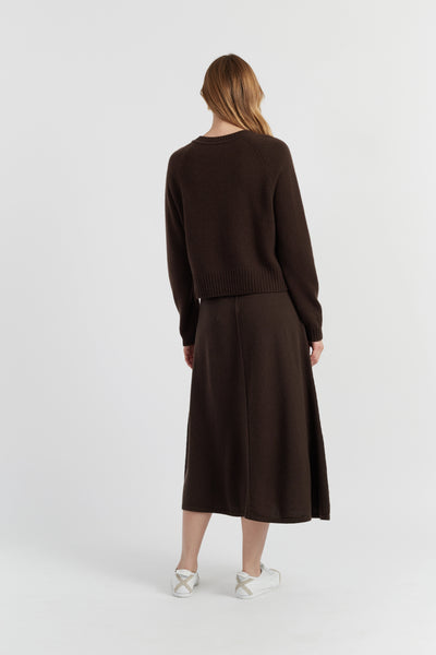 Woman wearing a brown sweater and skirt set on a white background