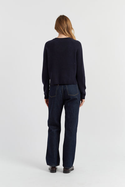 Person wearing a dark sweater and jeans on a white background