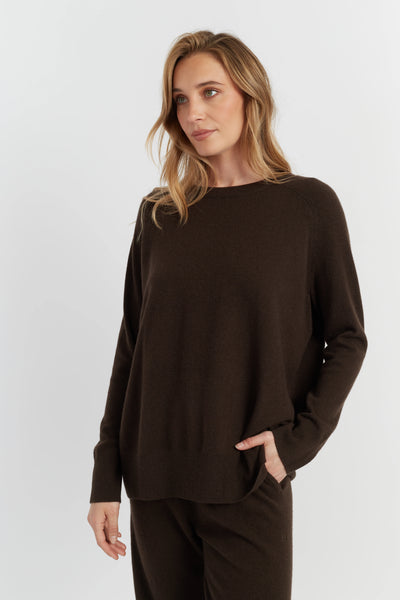 Woman wearing a brown sweater and pants on a white background