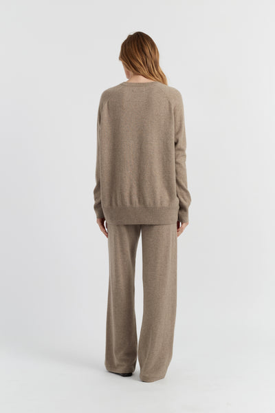 Person wearing a beige sweater and pants set on a white background