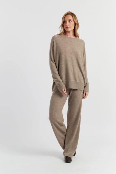Woman wearing a beige sweater and pants set on a white background