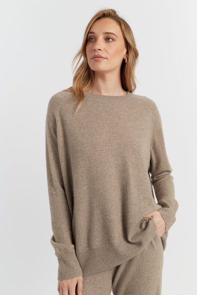Woman wearing a beige sweater and pants on a white background