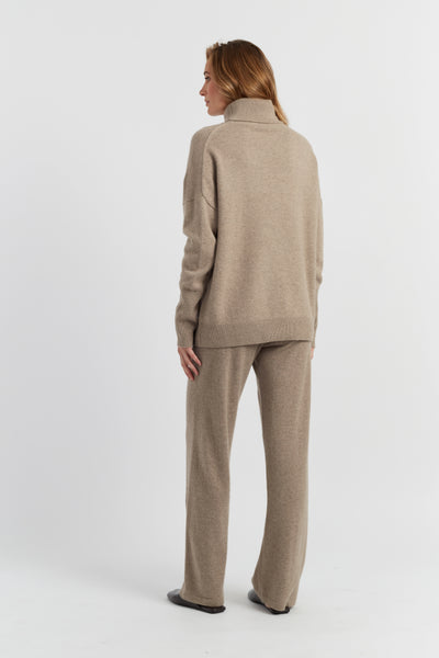 Woman wearing a beige sweater and pants set on a white background