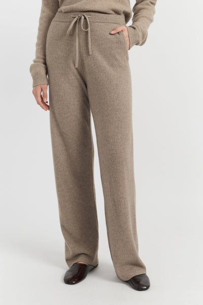 Beige lounge pants worn by a person on a white background