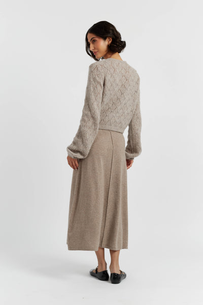 Woman wearing a beige knitted sweater and skirt on a white background
