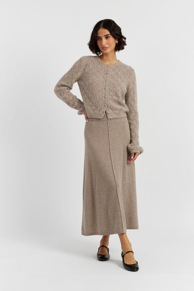 Woman wearing a beige knit sweater and skirt set on a white background