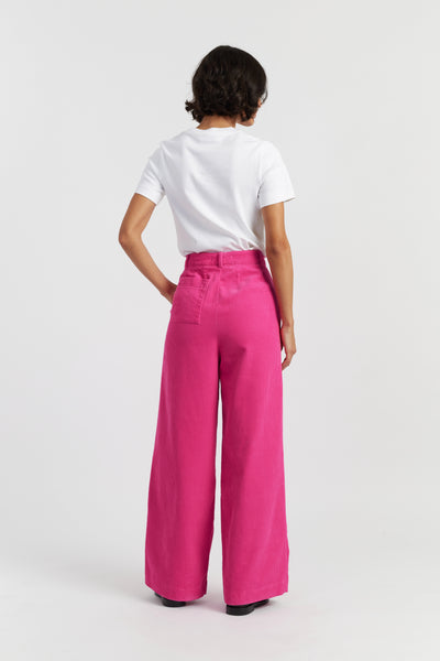 Person wearing a white sleeveless top and pink pants on a white background