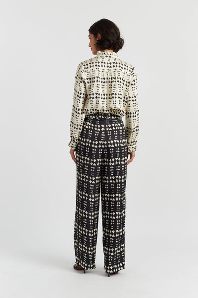 Woman wearing a patterned blouse and pants on a white background