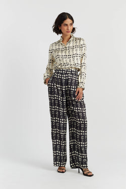 Woman wearing a patterned blouse and black and white checkered pants on a white background
