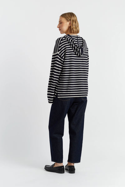 Person wearing a black and white striped sweater and dark pants on a white background