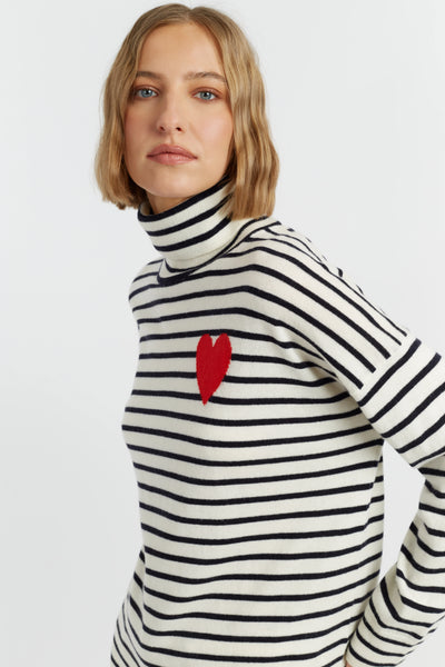 Woman wearing a black and white striped sweater with a red heart design on a light gray background