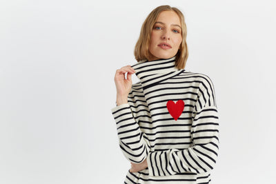 Woman wearing a black and white striped sweater with a red heart on a light gray background