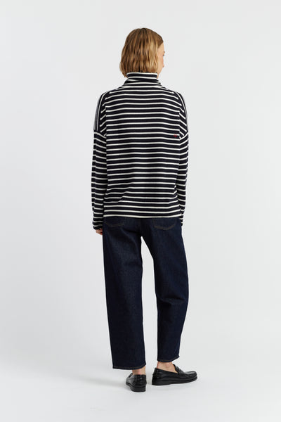 Person wearing a black and white striped shirt and dark pants on a white background