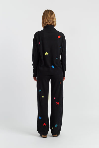 Person wearing a black outfit with colorful star patterns on a white background