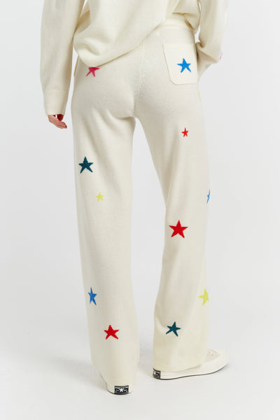 White pants with colorful star patterns worn by a person on a white background